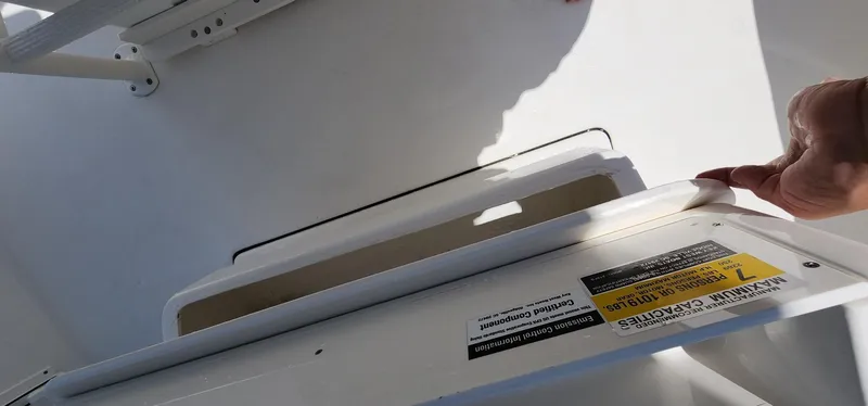 Slide: The Image of 2024 Key West 219fs boat compartment with safety label and hand opening hatch. - 31