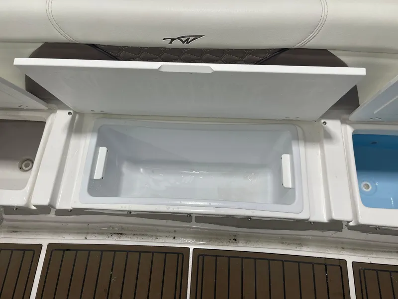 Slide: The Image of Open storage compartment on 2024 Tidewater 272LXF boat, featuring white interior and cushioned seating. - 25