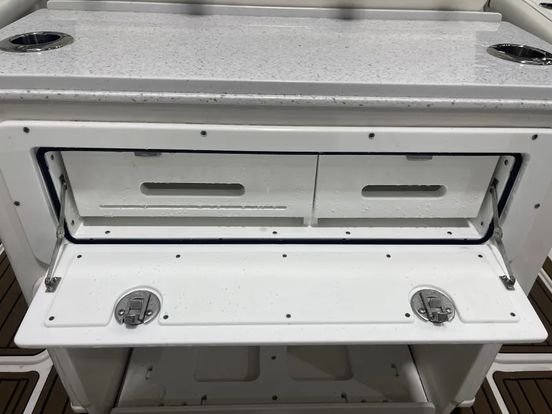 Slide: The Image of 2024 Tidewater 272LXF boat storage compartment with open hatch and cup holders. - 30