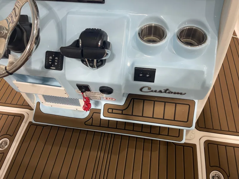 Slide: The Image of 2024 Tidewater 272LXF boat console with steering wheel, controls, and cup holders. - 36
