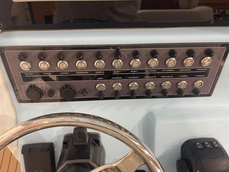 Slide: The Image of Control panel of 2024 Tidewater 272LXF boat with labeled switches and steering wheel. - 39