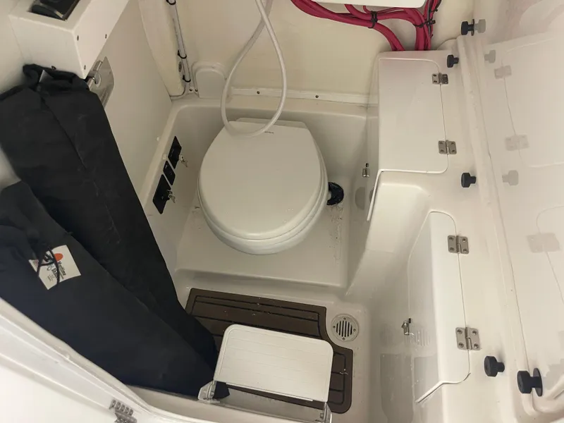 Slide: The Image of 2024 Tidewater 272LXF boat interior with compact marine toilet and storage compartments. - 46