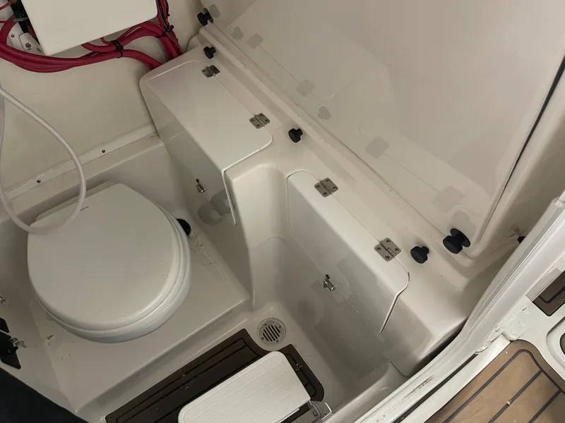 Slide: The Image of 2024 Tidewater 272LXF boat interior with compact marine toilet and storage compartments. - 48