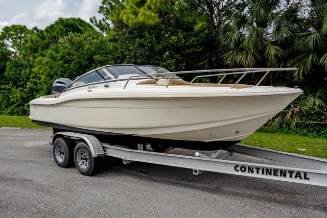 Slide: The Image of 2021 Scout 210 Dorado boat on trailer, surrounded by lush greenery. - 0