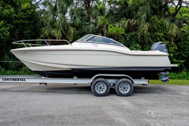 Slide: The Image of 2021 Scout 210 Dorado boat on trailer, parked near lush greenery. - 1