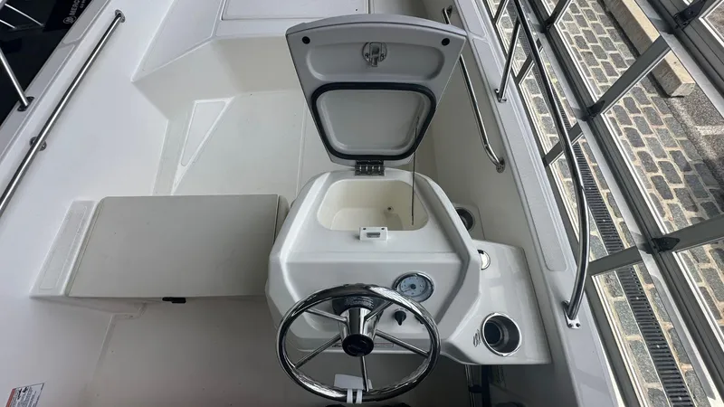 Slide: The Image of 2025 Boston Whaler 160 Super Sport interior with open storage compartment and steering wheel. - 11