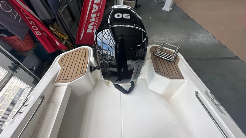 Slide: The Image of 2025 Boston Whaler 160 Super Sport boat interior with motor and wooden deck accents. - 6