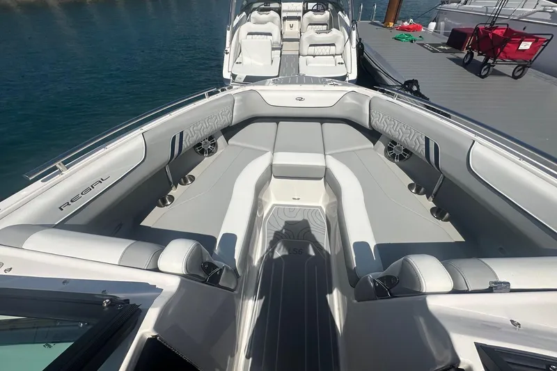 Slide: The Image of 2025 Regal LS6 Surf boat with luxurious seating, docked in a scenic urban marina. - 10