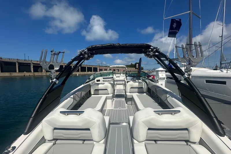 Slide: The Image of 2025 Regal LS6 Surf boat docked in urban marina with city skyline backdrop. - 3