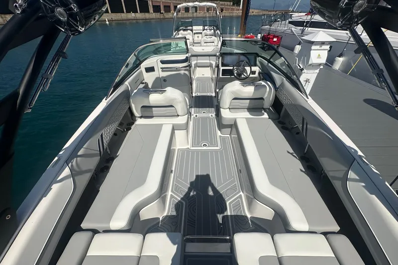 Slide: The Image of 2025 Regal LS6 Surf boat interior with modern dashboard and seating, docked under blue skies. - 5