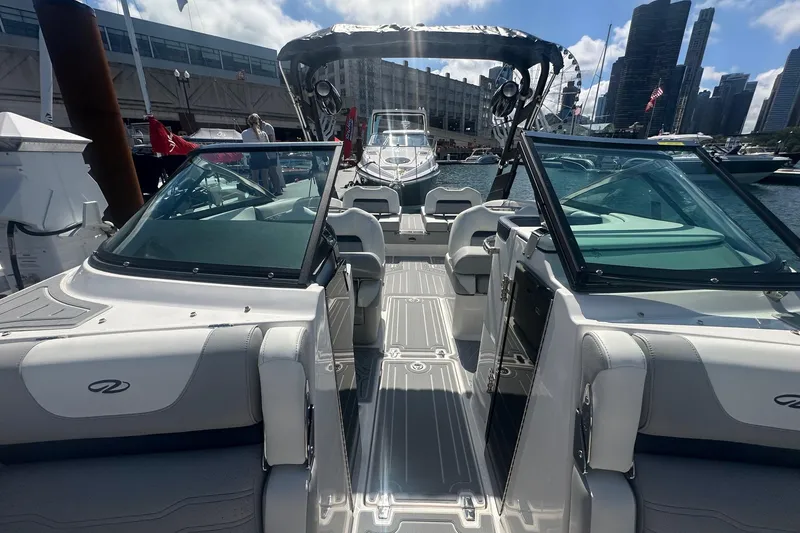 Slide: The Image of 2025 Regal LS6 Surf boat docked with city skyline and Ferris wheel in background. - 8