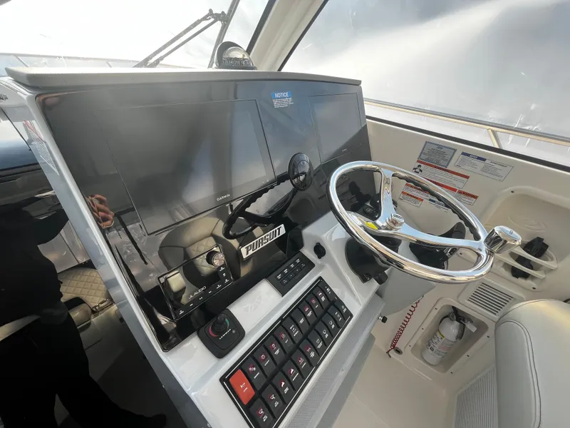 Slide: The Image of 2024 Pursuit OS 325 boat helm with steering wheel and control panel. - 13