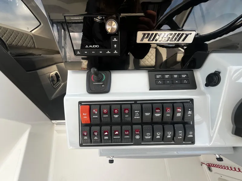 Slide: The Image of Control panel of 2024 Pursuit OS 325 boat with switches and audio system. - 15