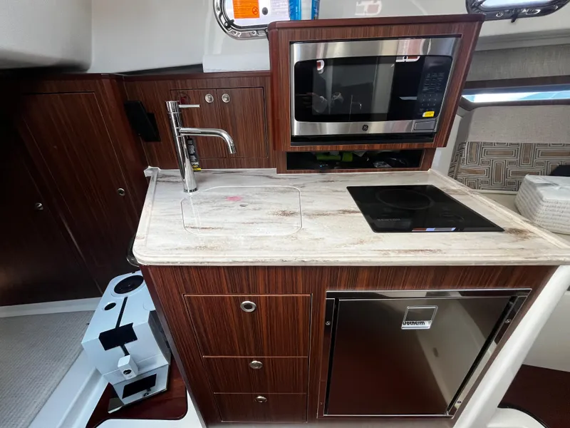 Slide: The Image of 2024 Pursuit OS 325 yacht kitchen with microwave, sink, and stove. - 22