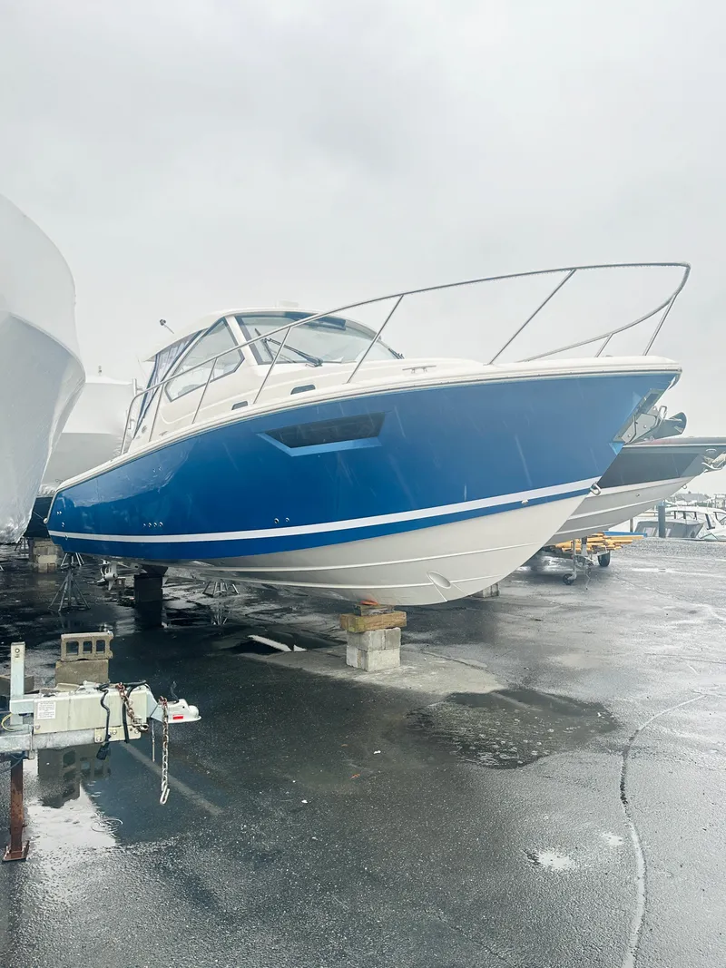 Slide: The Image of 2024 Pursuit OS 325 boat on a wet dock, blue and white exterior. - 26