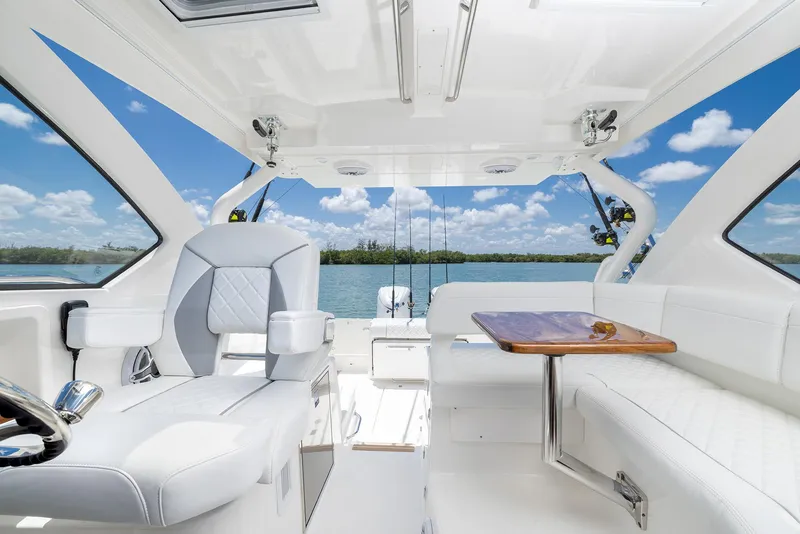 Slide: The Image of Luxurious 2024 Pursuit OS 325 yacht interior with white seating and wooden table, overlooking serene waters. - 31