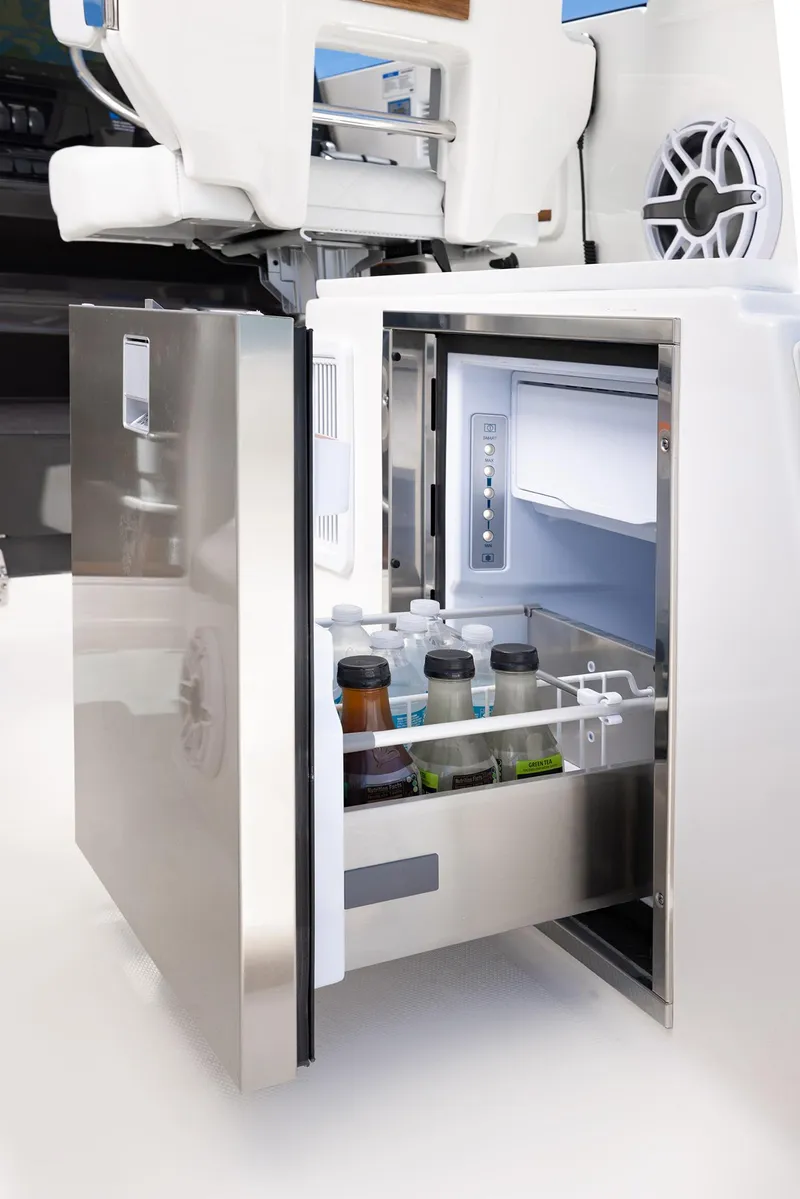 Slide: The Image of 2024 Pursuit OS 325 boat interior with open mini fridge stocked with beverages. - 32
