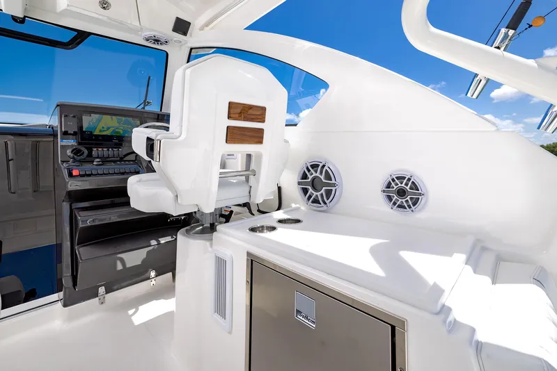 Slide: The Image of 2024 Pursuit OS 325 boat interior with helm, seating, and navigation equipment under clear blue sky. - 36