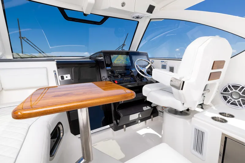 Slide: The Image of 2024 Pursuit OS 325 boat interior with helm, wooden table, and navigation equipment. - 37