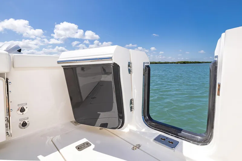 Slide: The Image of 2024 Pursuit OS 325 boat interior with open hatch, overlooking serene water and blue sky. - 44
