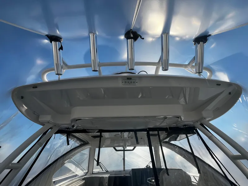 Slide: The Image of 2024 Pursuit OS 325 boat interior with rod holders and clear canopy. - 8