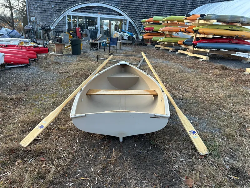Slide: The Image of White Puffin 860 boat with oars, surrounded by colorful kayaks, outdoors. - 4