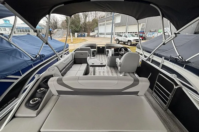 Slide: The Image of 2025 Bennington SX 22 Swingback boat interior with gray seating and marina backdrop. - 12