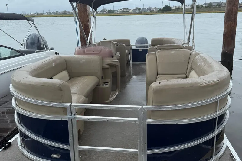 Slide: The Image of 2022 Starcraft LX 22 R pontoon boat with beige seating, docked on a calm lake. - 2