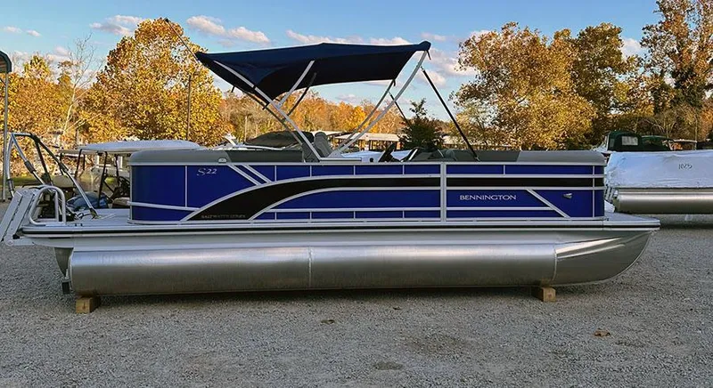 Slide: The Image of 2025 Bennington 21 S STERN RADIUS pontoon boat with blue accents, parked outdoors. - 0
