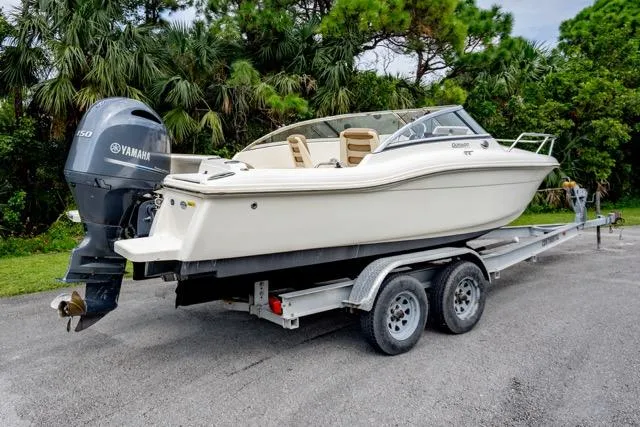 Slide: The Image of 2021 Scout 210 Dorado boat on trailer with Yamaha engine, parked near lush greenery. - 4