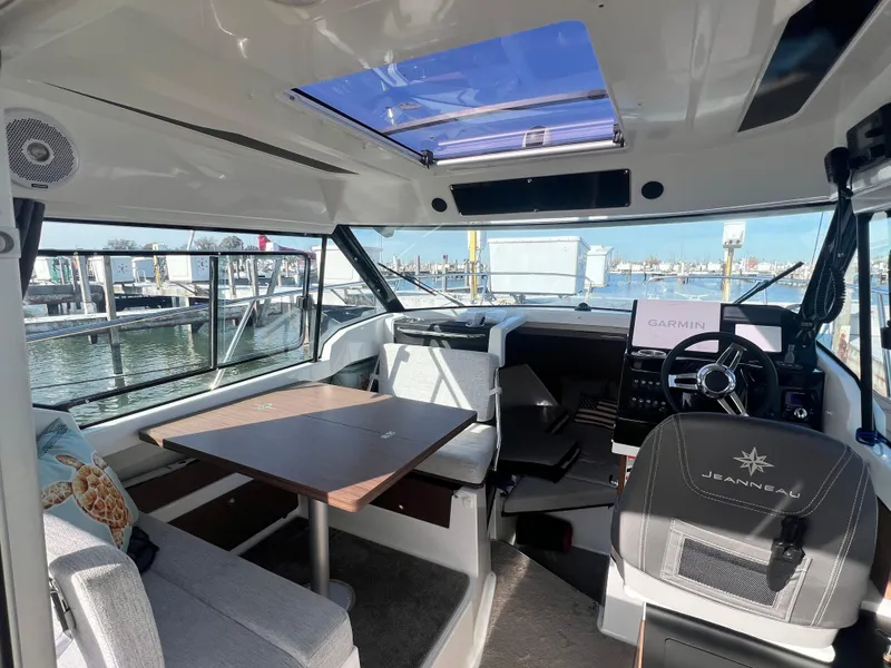 Slide: The Image of 2022 Jeanneau NC 795 S2 boat interior with seating, table, and helm at marina. - 21