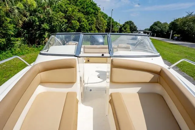 Slide: The Image of 2021 Scout 210 Dorado boat interior with tan seating, surrounded by lush greenery. - 7