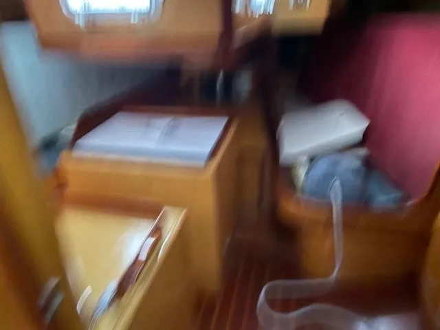 Slide: The Image of Blurry interior of 1984 Farr 44 Custom yacht with wooden furnishings and red seating. - 13