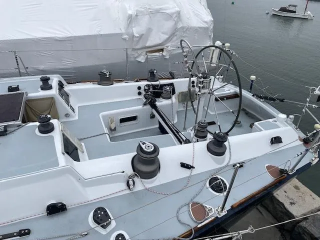 Slide: The Image of 1984 Farr 44 Custom sailboat cockpit with steering wheel, winches, and rigging, docked by the water. - 21