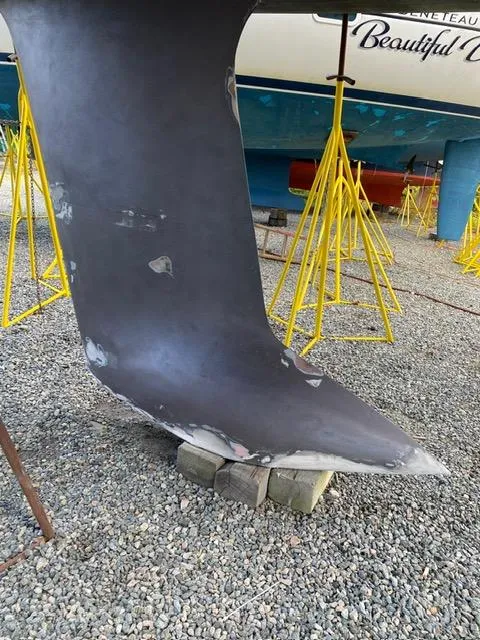 Slide: The Image of Keel of 1984 Farr 44 Custom sailboat on stands, gravel ground. - 6