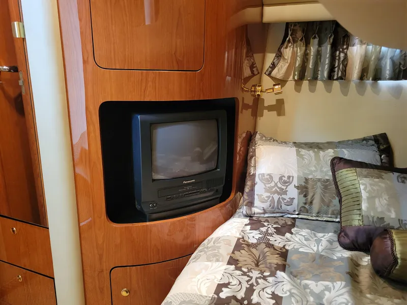 Slide: The Image of 2001 Sea Ray 450 Express Bridge cabin with TV and patterned bedding. - 23