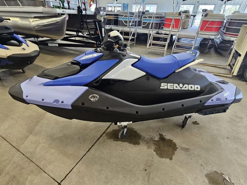 Slide: The Image of 2025 Sea-Doo Spark™ jet ski, blue and black, displayed indoors on a stand. - 3