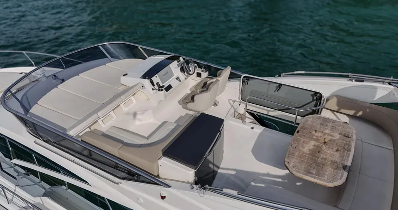 Slide: The Image of 2017 Absolute 50 Fly yacht flybridge with seating, helm, and table on calm water. - 6