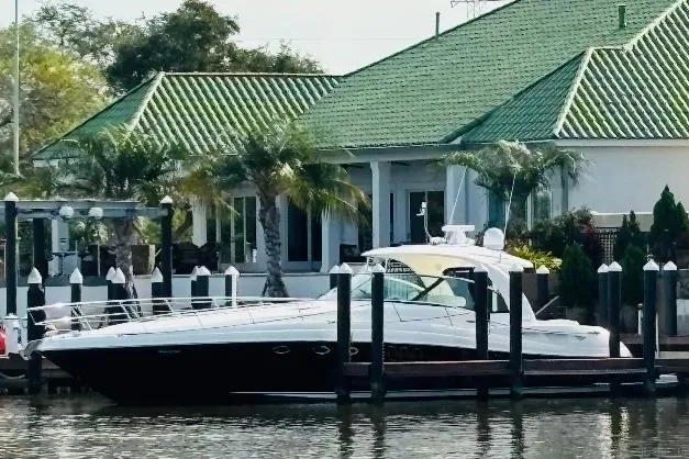 The Image of 2007 Sea Ray 52 Sundancer yacht docked by a waterfront house with green roof. - 0