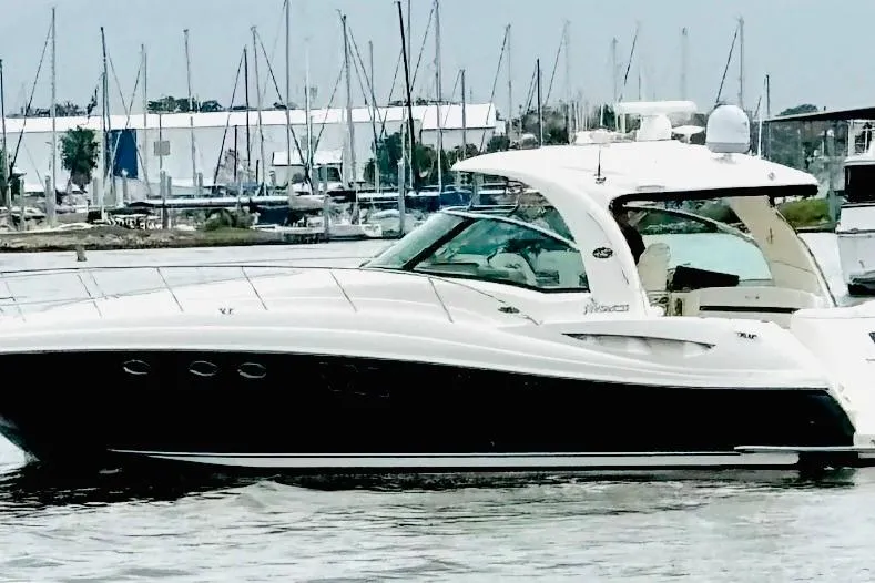 Slide: The Image of 2007 Sea Ray 52 Sundancer yacht docked at a marina with sailboats in the background. - 2