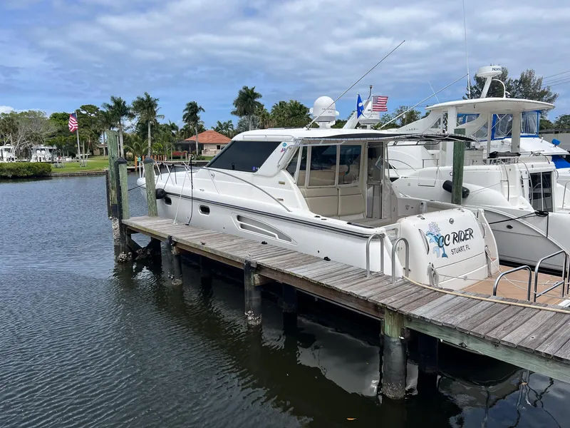 Slide: The Image of 2004 Tiara Yachts 4400 Sovran docked by a wooden pier, under a partly cloudy sky. - 48