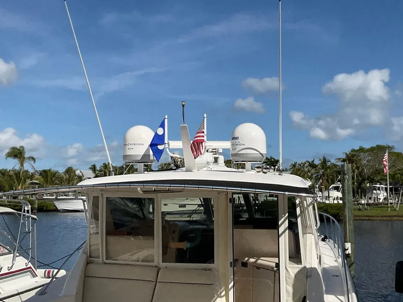 Slide: The Image of 2004 Tiara Yachts 4400 Sovran docked, featuring radar domes and flags under a clear sky. - 50