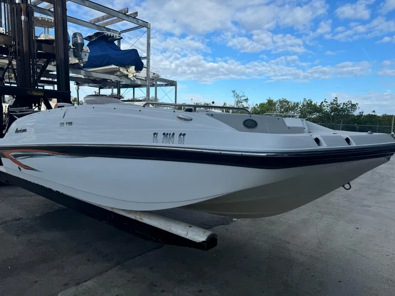 Slide: The Image of 2021 Hurricane 188 SunDeck Sport CC-OB boat on a lift under a blue sky. - 2