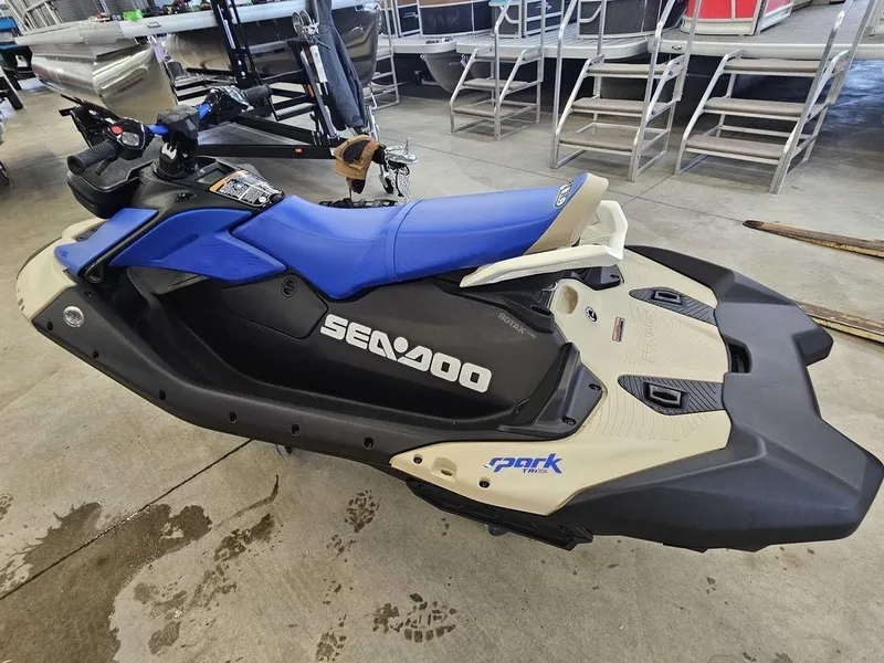 Slide: The Image of 2025 Sea-Doo Spark Trixx jet ski in showroom, blue and black design. - 7