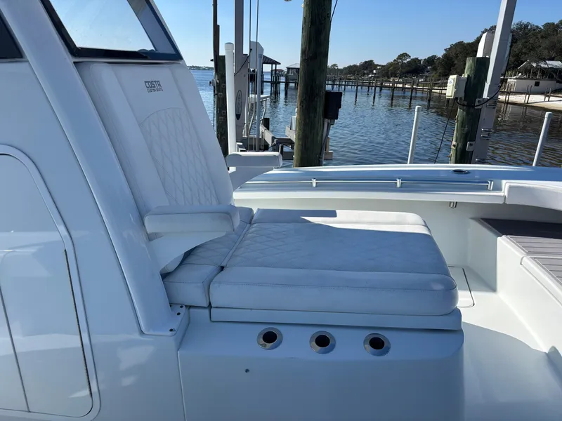 Slide: The Image of 2022 Costa Custom Boats 264HC with white seating, docked by a serene waterfront. - 12