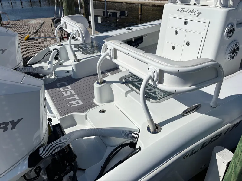 Slide: The Image of 2022 Costa Custom Boats 264HC interior with seating and storage, docked by the water. - 21