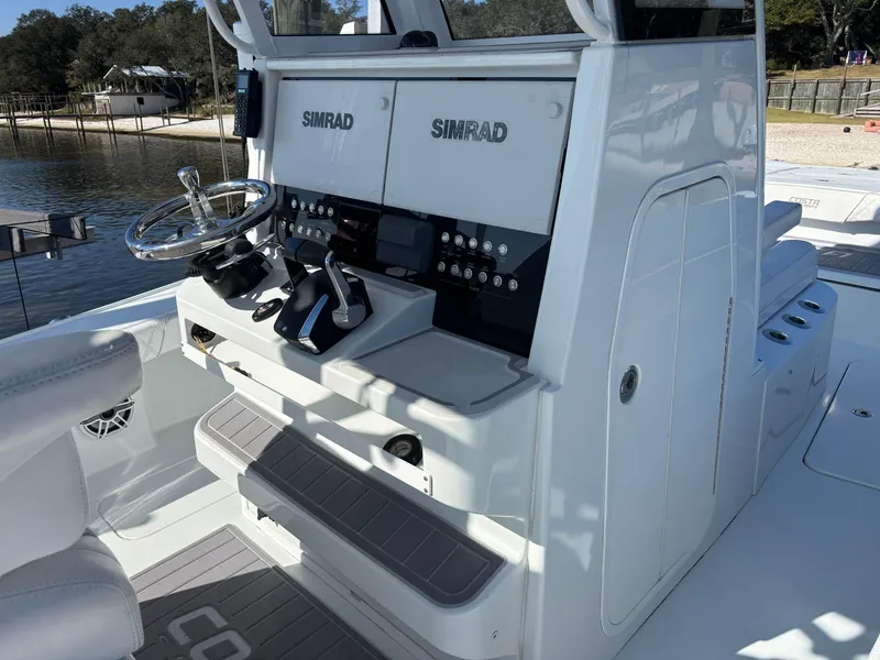 Slide: The Image of 2022 Costa Custom Boats 264HC helm with Simrad electronics, sleek design, and waterfront view. - 22