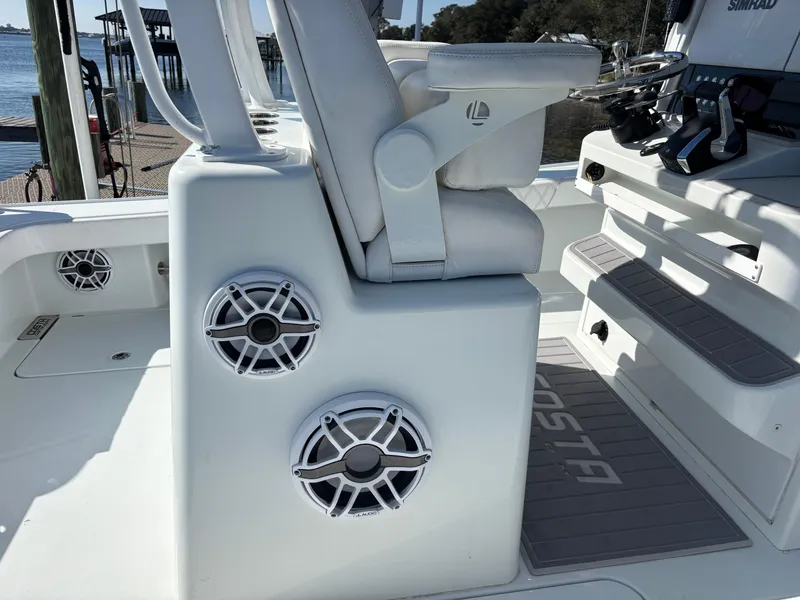 Slide: The Image of 2022 Costa Custom Boats 264HC interior with speakers and seating, dockside view. - 24