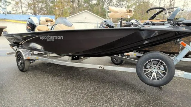 Slide: The Image of 2025 G3 Sportsman 1710 boat on trailer, sleek black design, parked outdoors. - 1