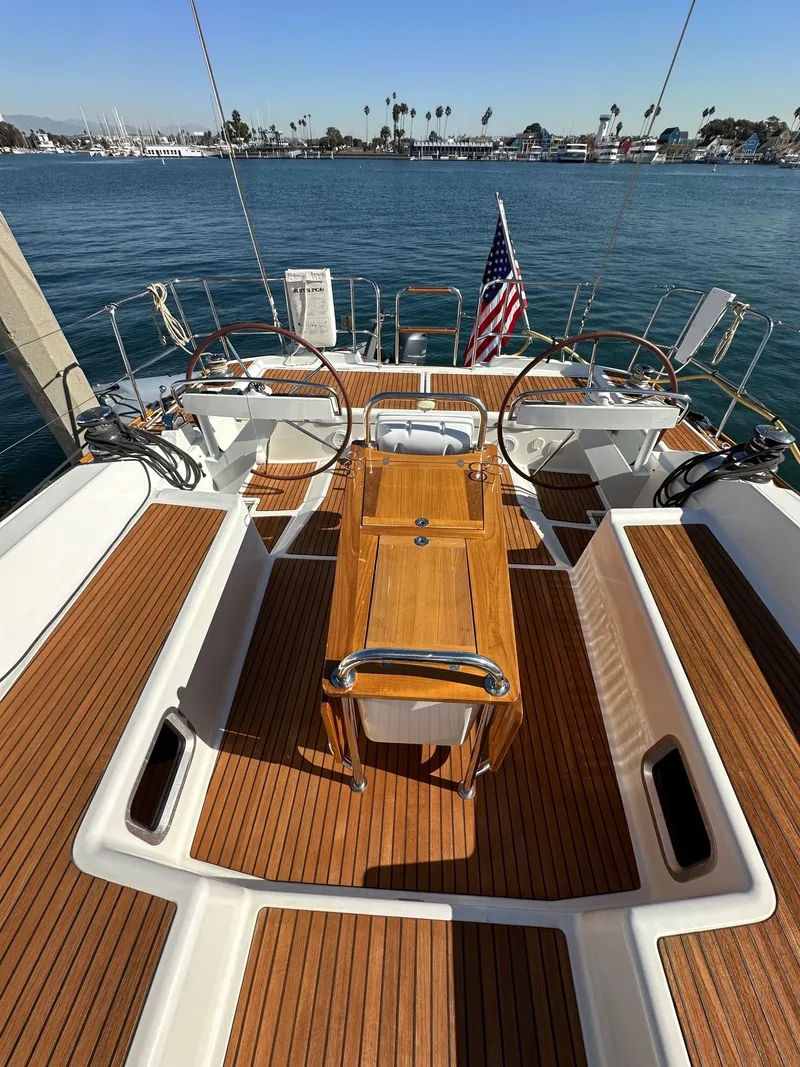 Slide: The Image of 2013 Jeanneau 57 sailboat deck with wooden finish, dual steering wheels, and ocean view. - 29